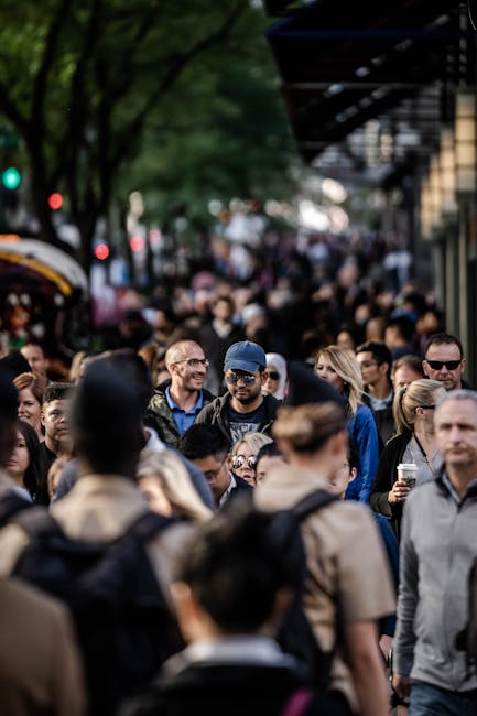 A bustling urban scene with diverse people walking on a tree-lined city street.