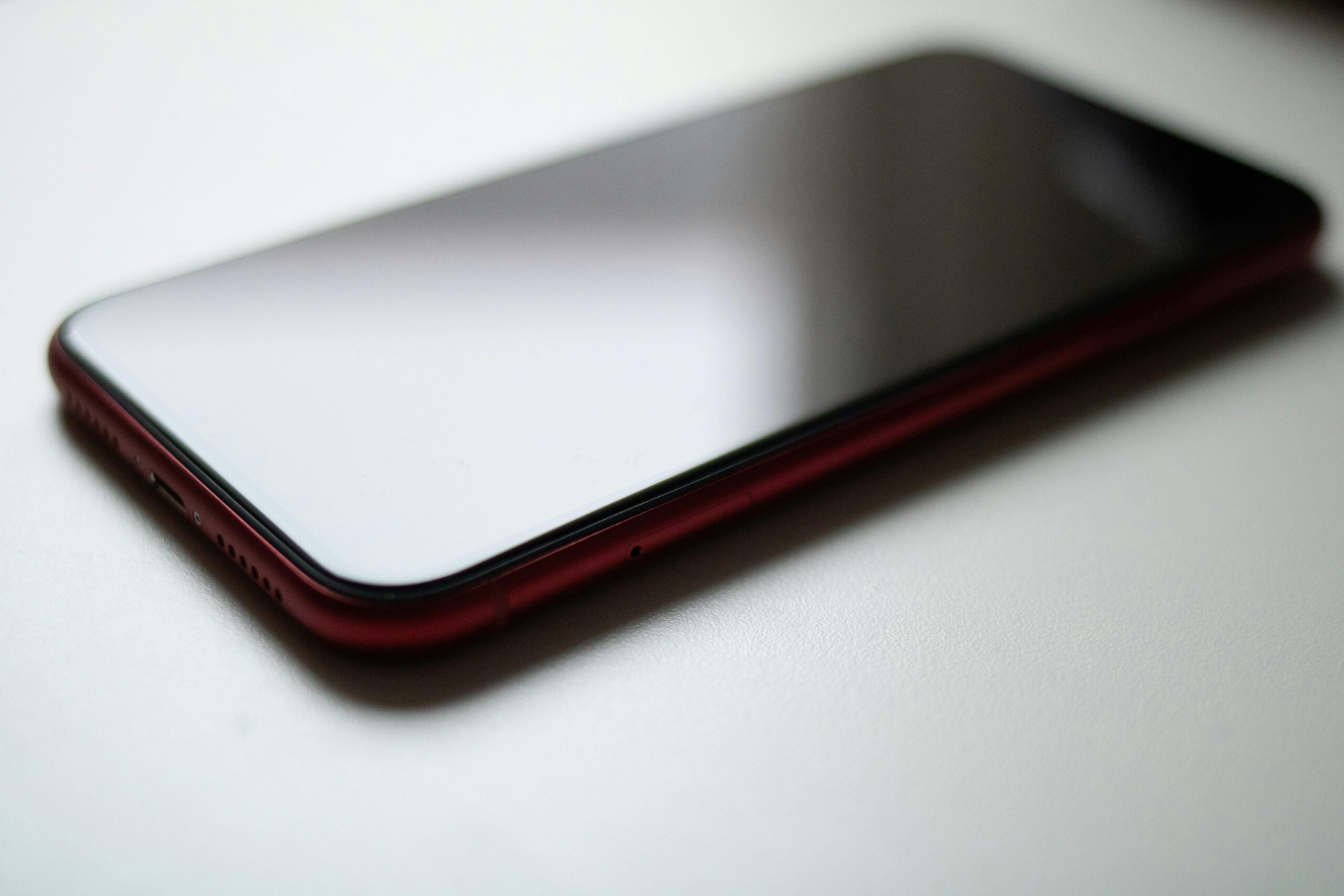 Close-up image of a red smartphone lying on a white surface with a modern sleek design.